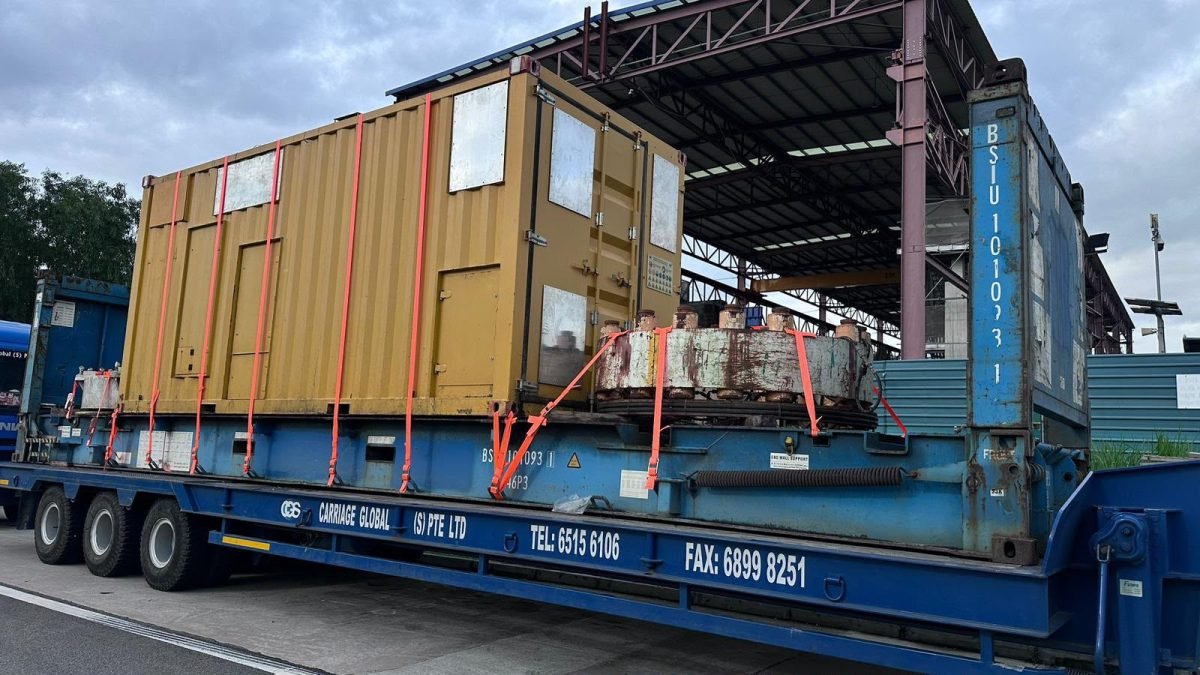 Carriage Global low-bed trailer hauling a project cargo module under a warehouse canopy